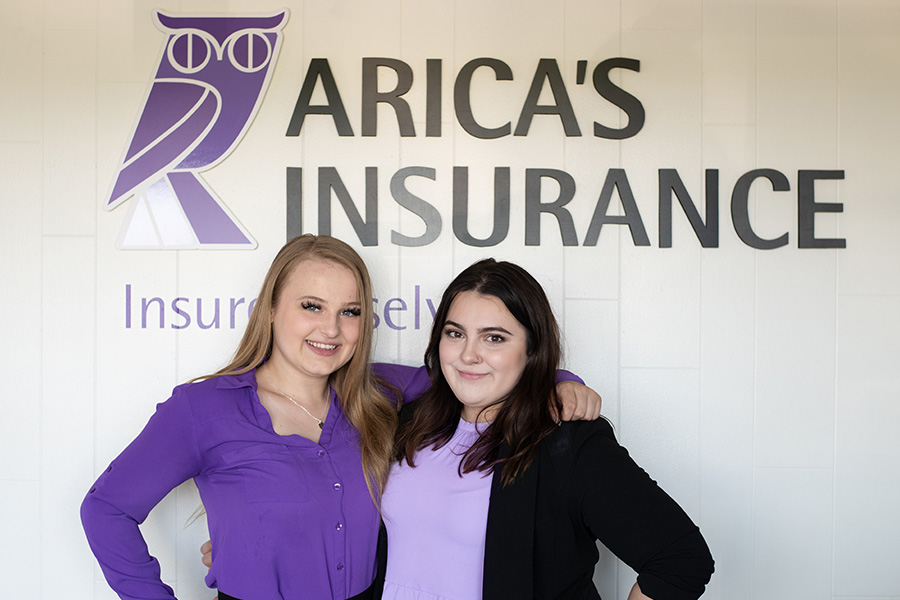 Specialized Business Insurance - Hannah and Carolee Standing Together in Arica's Insurance Office With Display of Owl Logo Behind Them on Wall